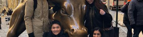 Five students posing with a Bull statue