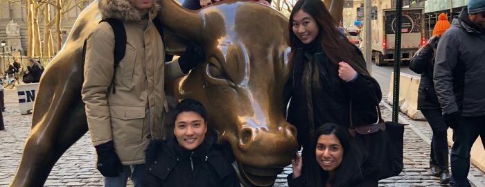 Five students posing with a Bull statue